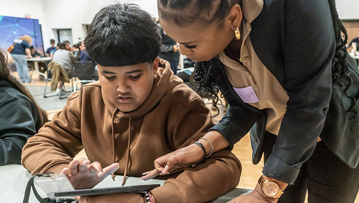 An adult and student work together on a budgeting exercise on a tablet.